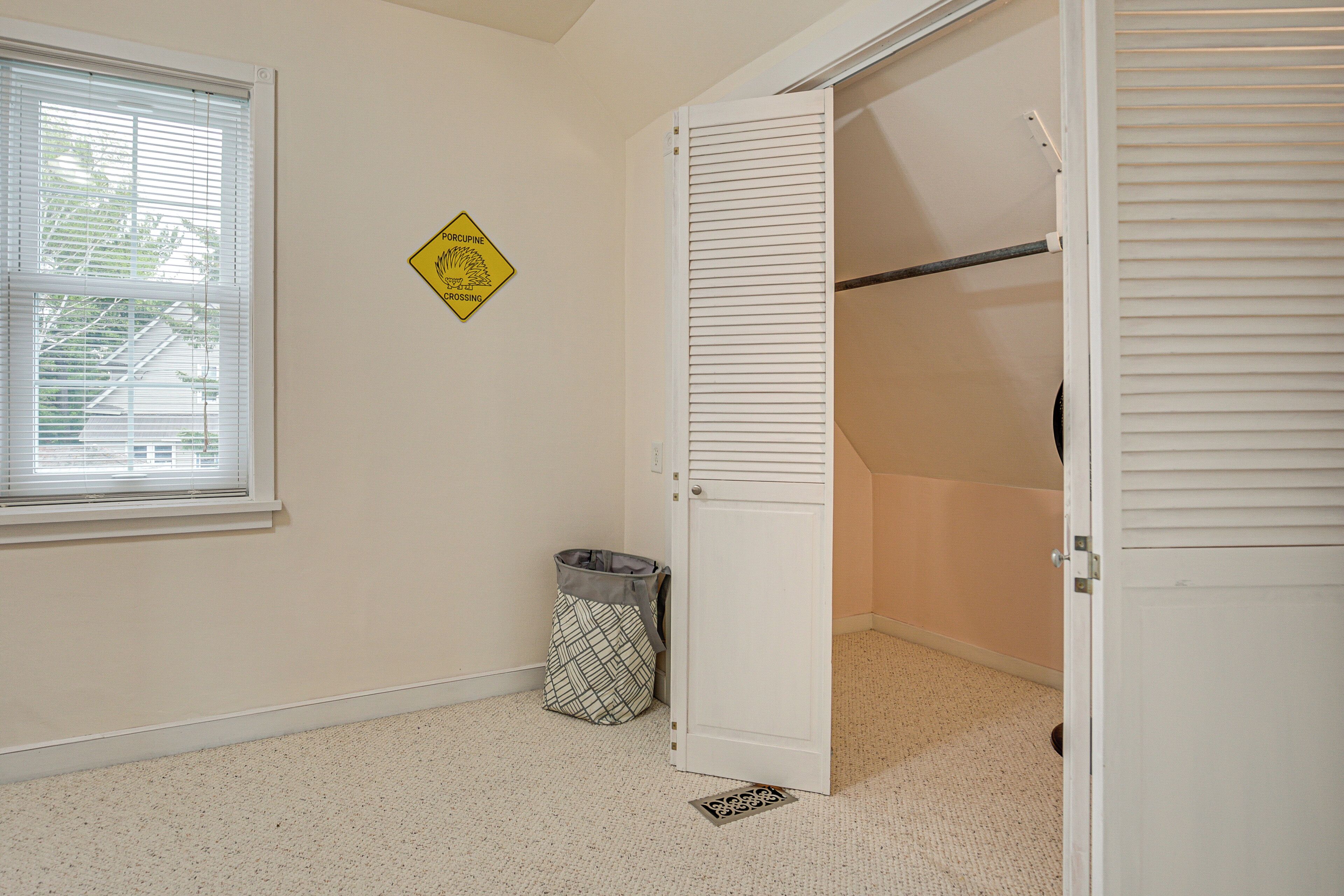 Una habitación con ventana, puerta, basurero y un letrero de precaución amarillo.