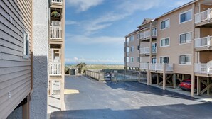 Edifício residencial com vários andares, varandas, área de estacionamento e vista para a praia.