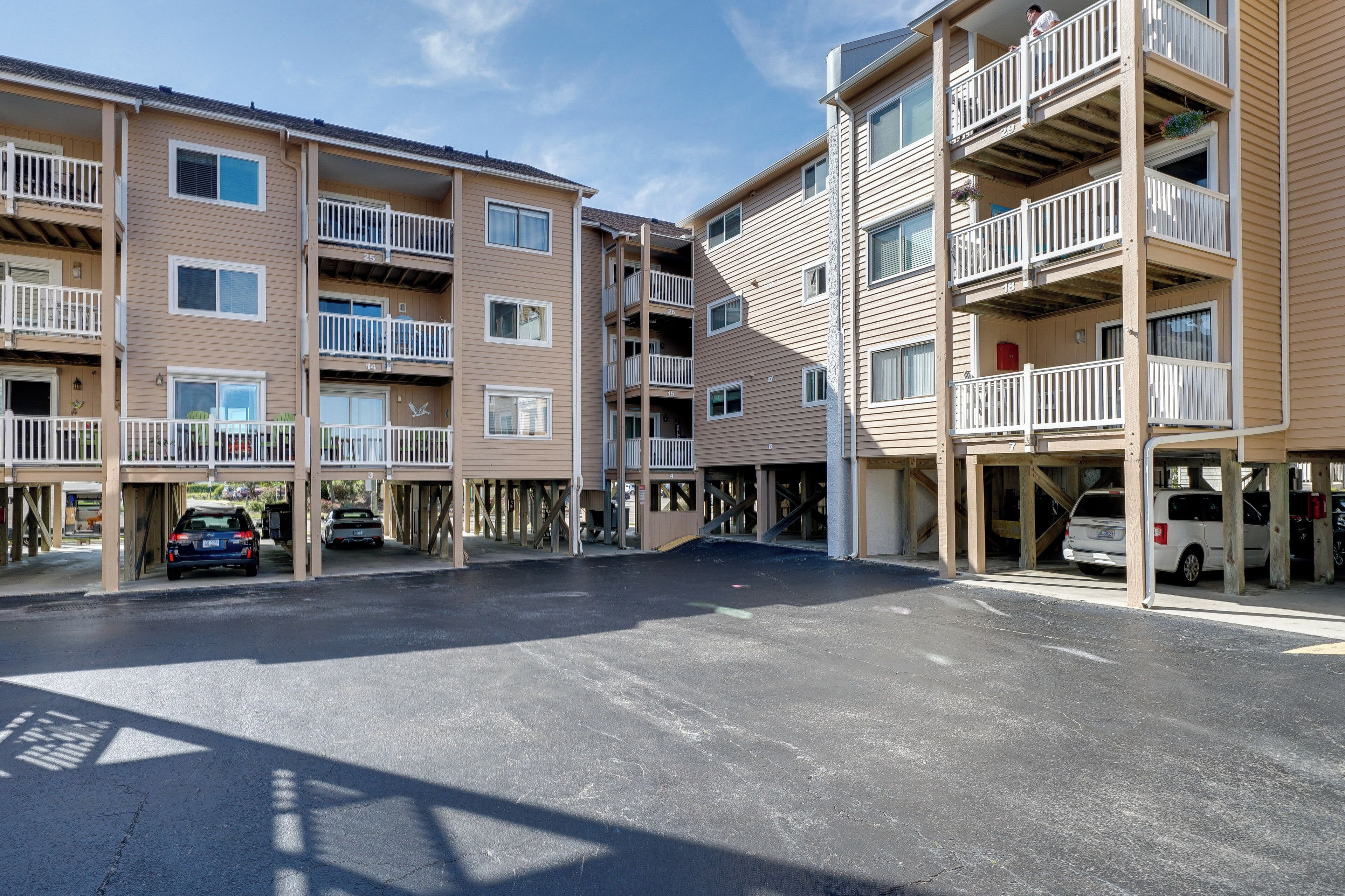 A multi-story residential building with balconies, parking garage, and a clear sky.