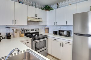 Una cocina moderna con armarios blancos, electrodomésticos de acero inoxidable, horno empotrado y microondas.