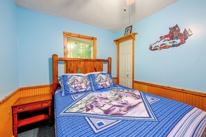 A bedroom with a wooden bed, a window, a door, and a wall decoration. - Peaceful Bryson City Cabin - Fire Pit & Hot Tub! (Bryson City)