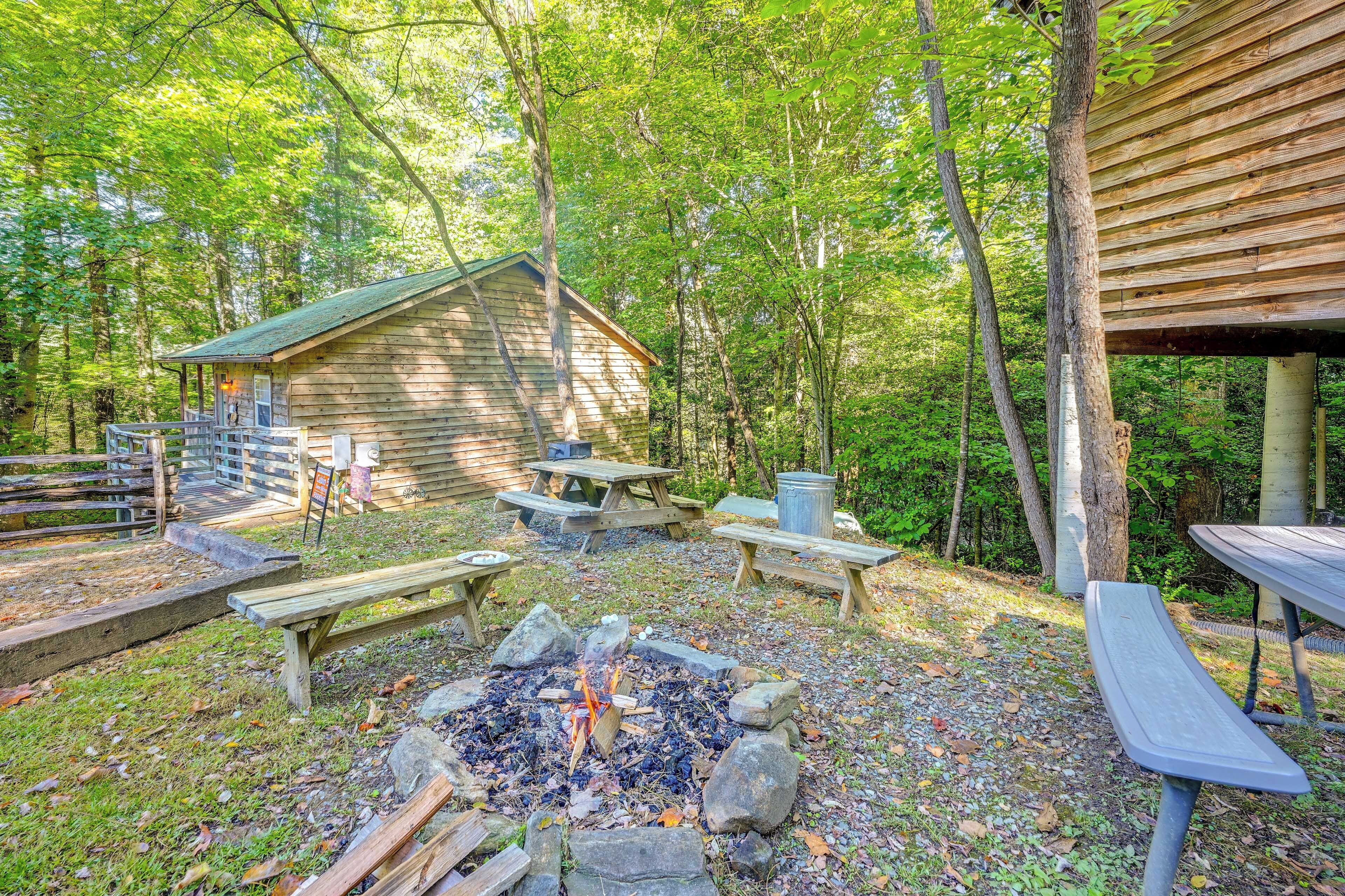 A rustic cabin with a fire pit, picnic tables, and a wooden deck.