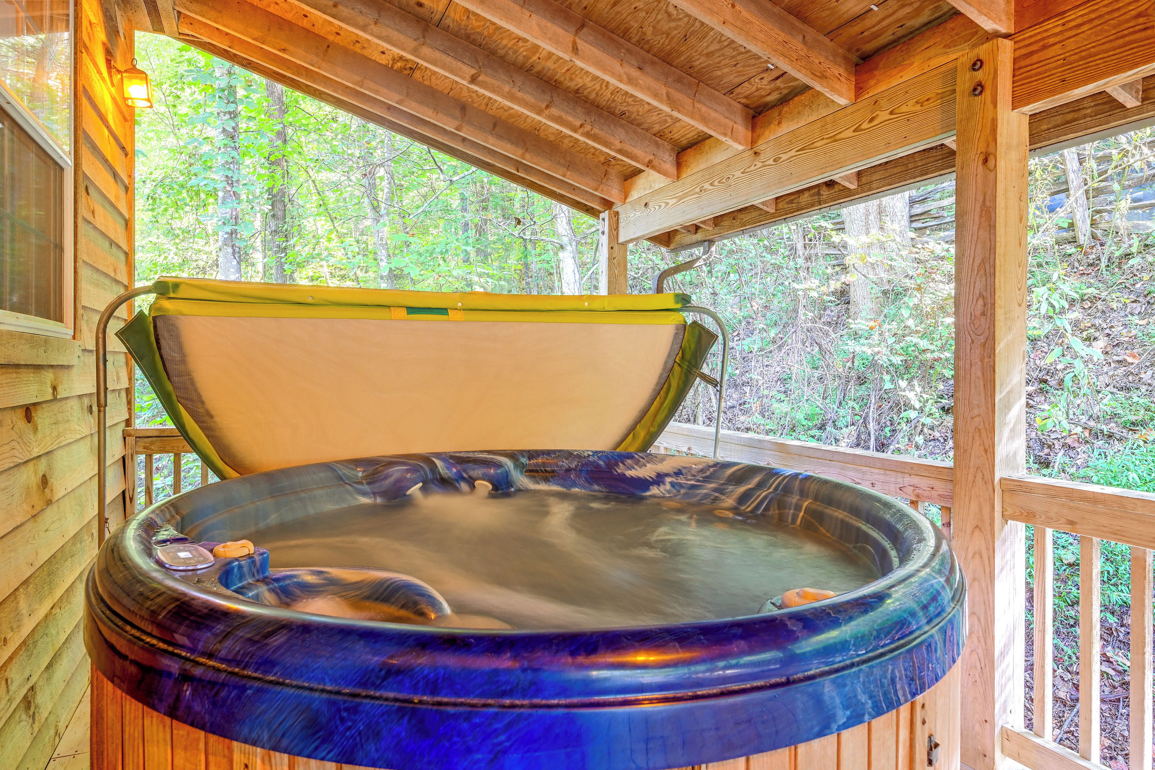 A hot tub with a wooden exterior, set in a wooden structure with a view of a forest.