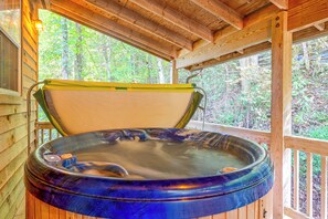 A hot tub with a wooden exterior, set in a wooden structure with a view of a forest. - Peaceful Bryson City Cabin - Fire Pit & Hot Tub! (Bryson City)