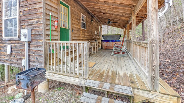 Een houten vakantiehuisje met een veranda, een groene deur en een brandblusser.