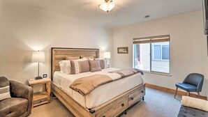 Un dormitorio con cama de madera, una mesita de noche, una silla y una ventana con persianas.