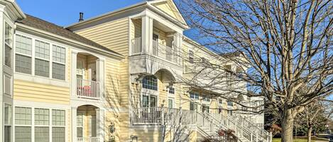 A two-story residential building with a central entrance, multiple balconies, and a well-maintained lawn.