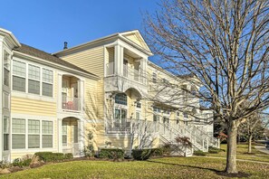 A two-story residential building with a central entrance, multiple balconies, and a well-maintained lawn.