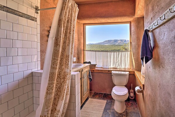 A bathroom with a view of mountains, a shower curtain, a sink, and a toilet.