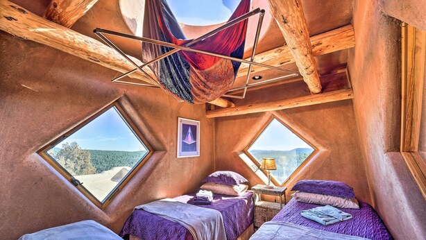A cozy, triangular-roofed room with two beds, a hammock, and large windows offering scenic views. - Peaceful New Mexico Retreat w/ Panoramic Mtn Views (Cleveland)