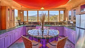 A kitchen with purple cabinets, a round table, and a view of mountains through large windows. - Peaceful New Mexico Retreat w/ Panoramic Mtn Views (Cleveland)