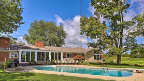 Una casa con piscina, patio cubierto y fachada de ladrillo.