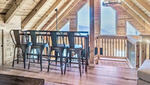 A wooden interior with a dining table and chairs, large windows, and a balcony. - Peaceful Free Union Cabin w/ Deck & Mtn Views (Dyke)