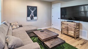 A living room with a sectional sofa, a coffee table, a TV, and a wooden cabinet. - Peaceful Free Union Cabin w/ Deck & Mtn Views (Dyke)