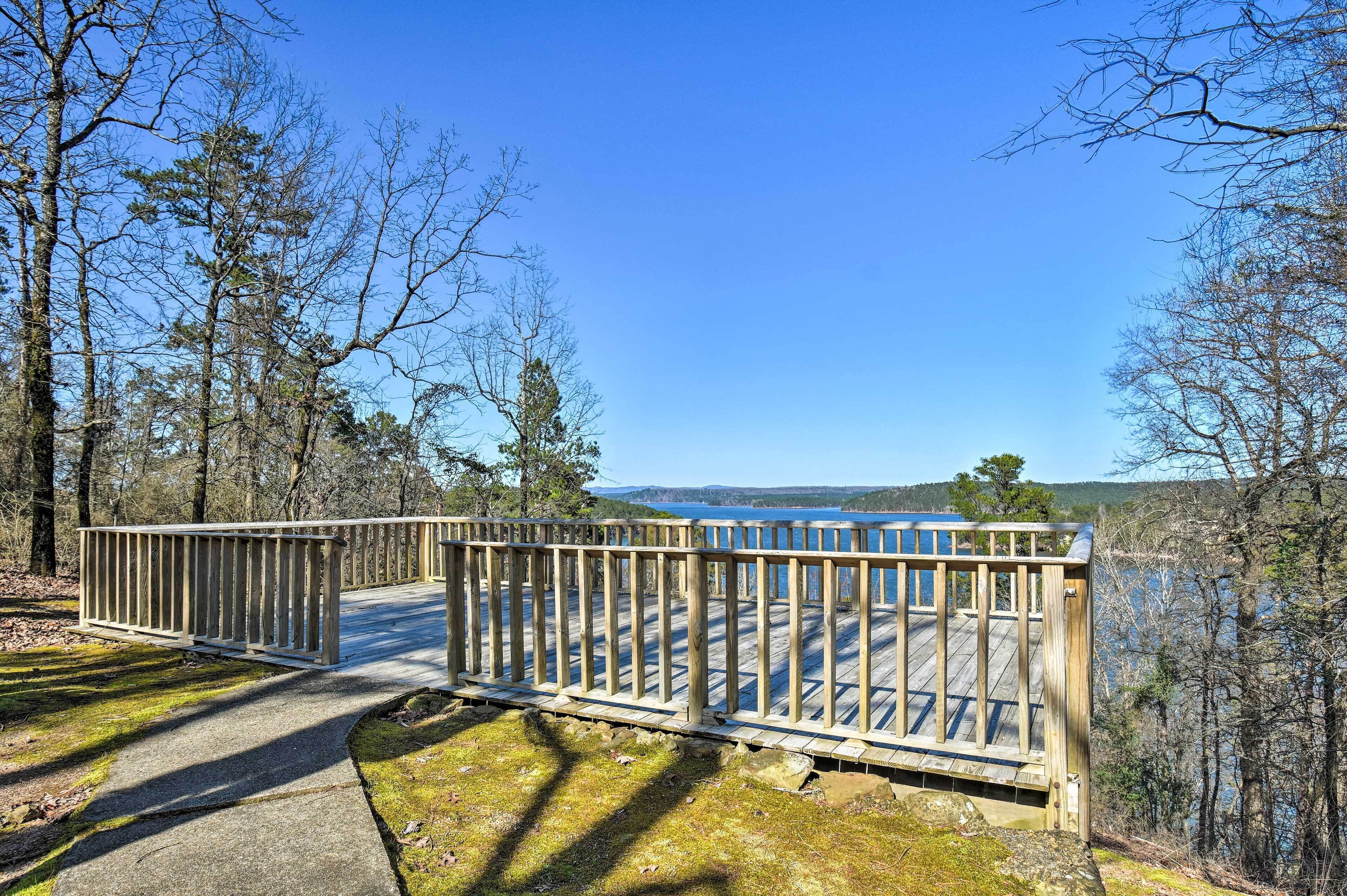 A wooden deck with a railing overlooking a body of water, surrounded by trees.