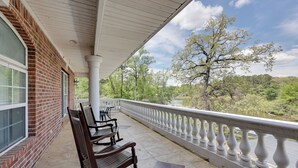 A covered balcony with a white balustrade, brick walls, and a view of a river and trees. - Game Room & Private Pool: Home in Hot Springs! (Hot Springs)