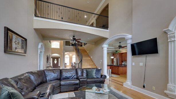 A spacious living room with a large leather sectional sofa, a glass coffee table, and a staircase leading to an upper level. - Game Room & Private Pool: Home in Hot Springs! (Hot Springs)