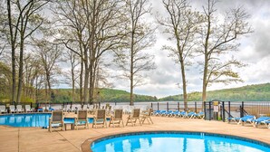 A swimming pool with lounge chairs and a fence, surrounded by trees and hills. - Community Perks & Deck: Lake Harmony Townhome! (Lake Harmony)