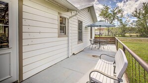 Un patio techado con una mesa, sillas y un banco, y vistas del paisaje circundante.