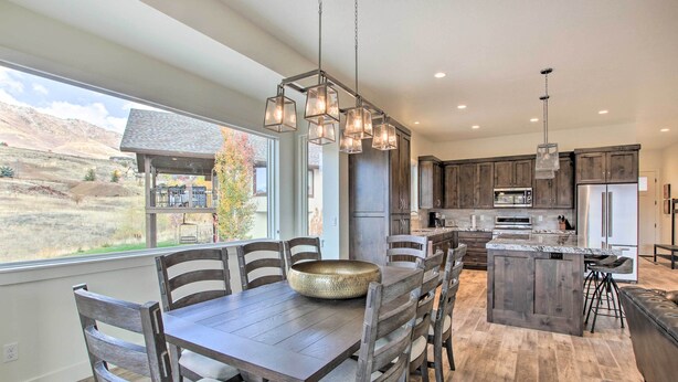 A modern kitchen with dark wooden cabinets, a large island with bar stools, and a hanging light fixture.