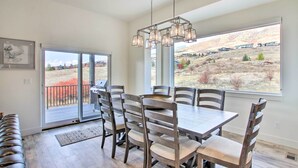 A dining area with a large table and chairs, a bench, and a view of a mountainous landscape through large windows.