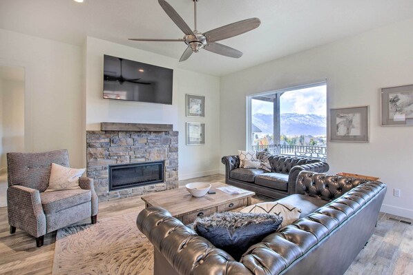 A living room with a stone fireplace, leather sofas, and a ceiling fan. - Scenic Eden Gem w/ Hot Tub ~ 6 Mi to Ski Area (Eden)