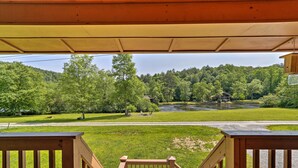 Una terraza de madera con vistas a un paisaje verde, que incluye un río y colinas boscosas.