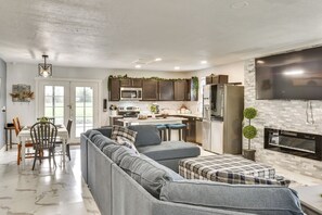 A modern kitchen with dark cabinets, a large island, and a flat-screen TV above the fireplace.