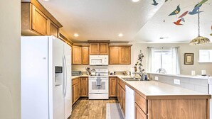 A kitchen with wooden cabinets, a white refrigerator, a microwave, and a stove. - Prismatic Boise Retreat w/ Fenced Backyard! (Boise)