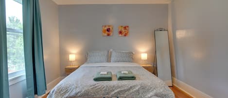 A neatly made bed with floral bedding, two bedside lamps, and a large mirror on the wall.