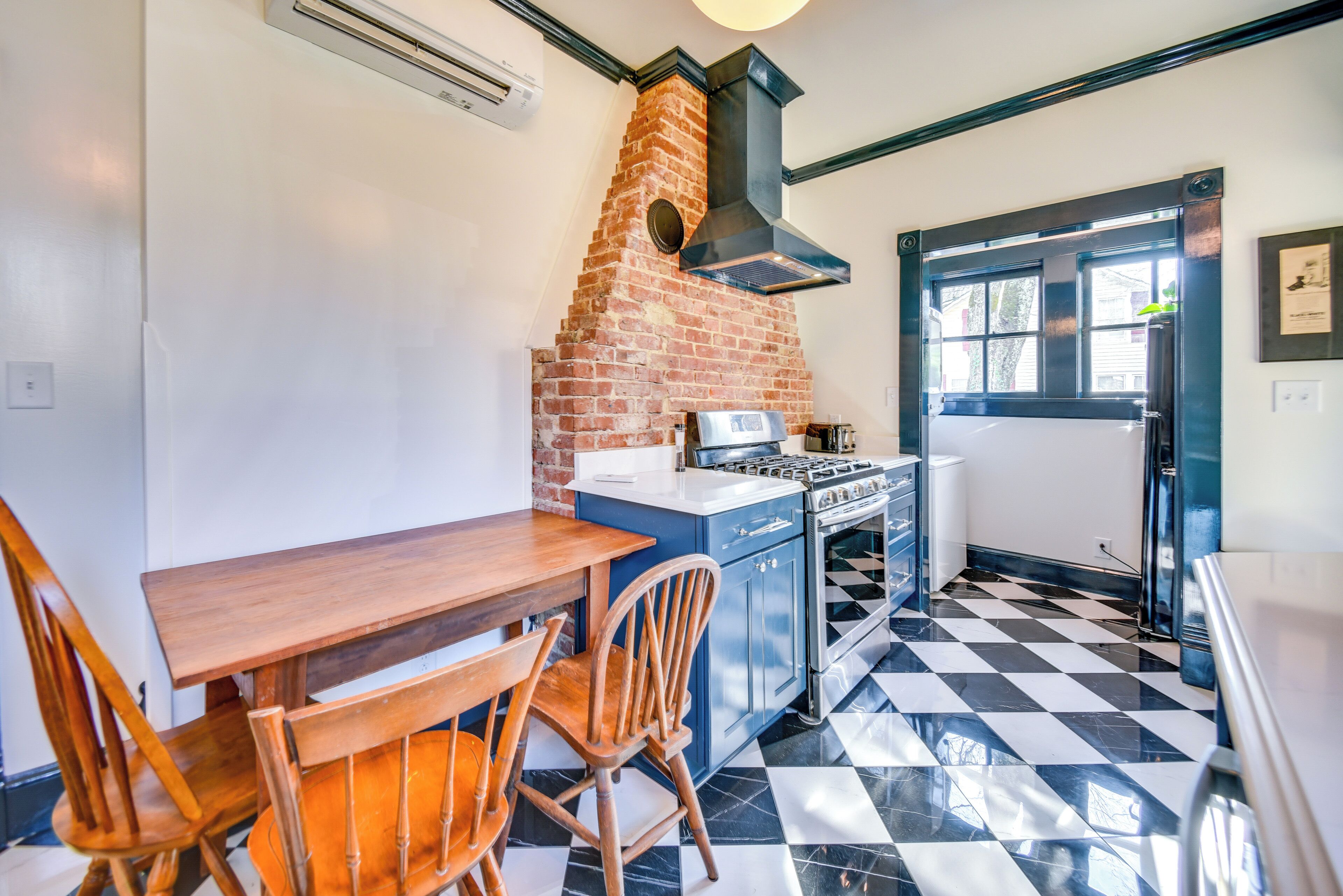 Una cocina con horno de ladrillo, estufa y piso a cuadros.