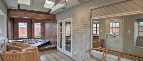 A spacious room with a large ceiling fan, a built-in bench, and a view of the outside.