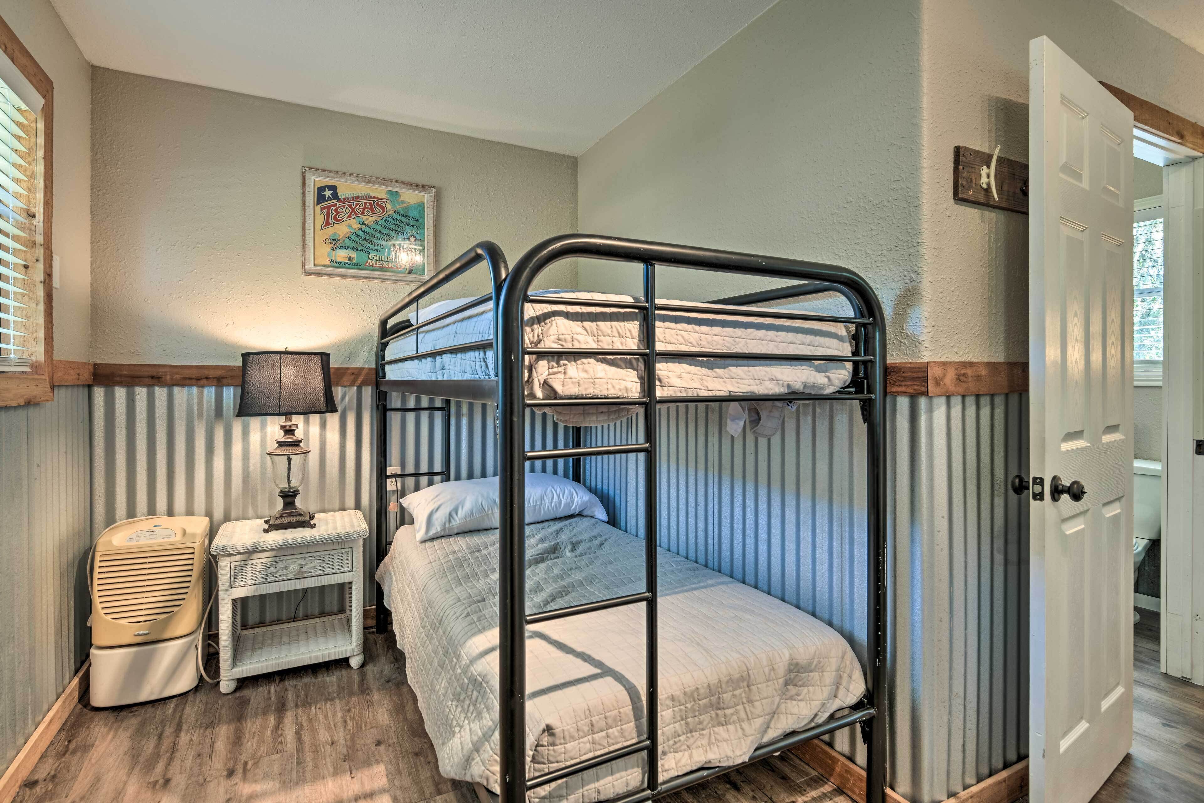 A bunk bed room with a lamp, a vintage radio, and a Texas-themed poster on the wall.