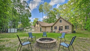 A house with a fire pit in the yard, surrounded by four chairs. - Higgins Lake Getaway - Boating, Fish, Golf, Atv! (Roscommon)