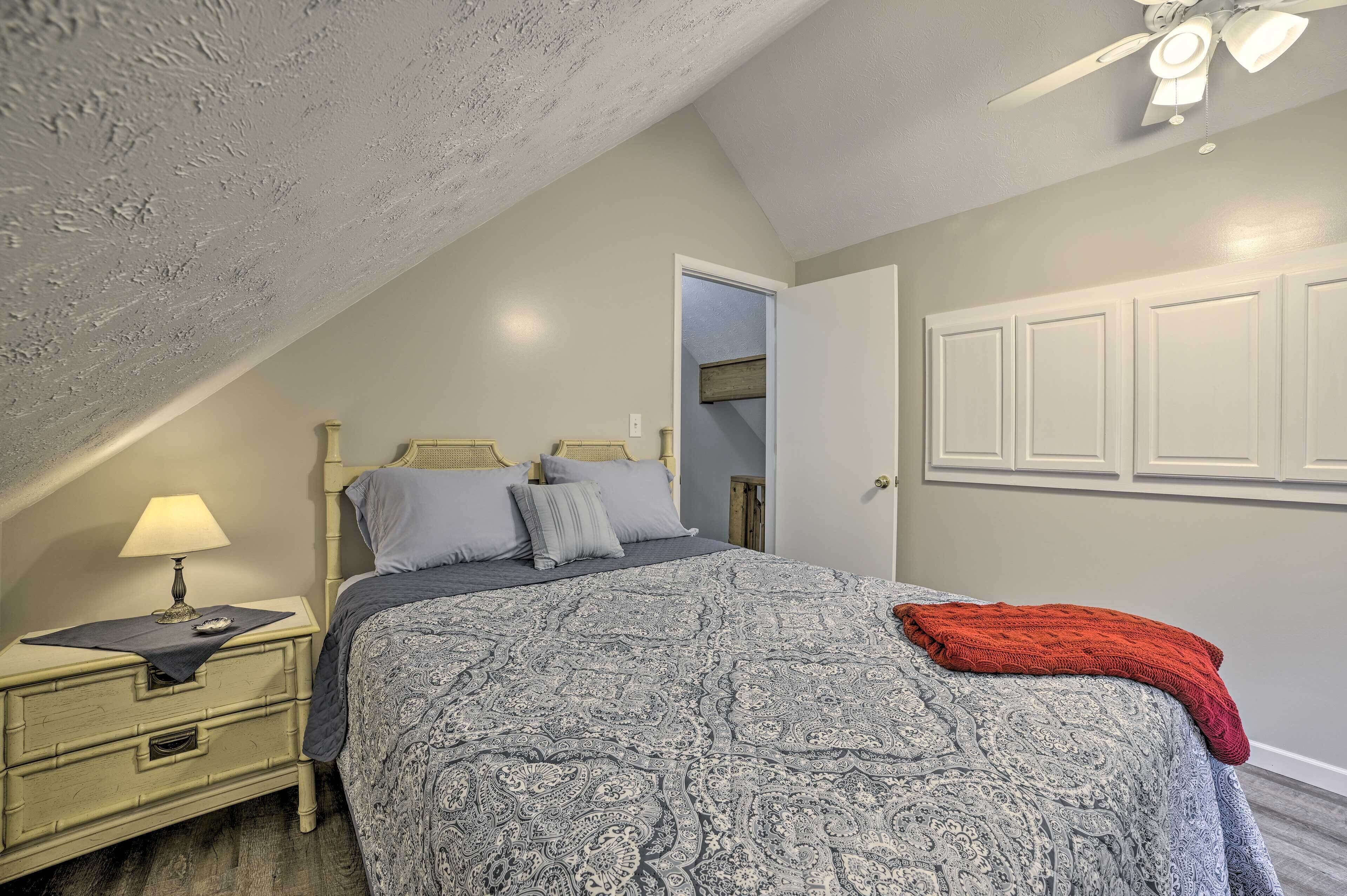 A bedroom with a bed, nightstand, and a ceiling fan.
