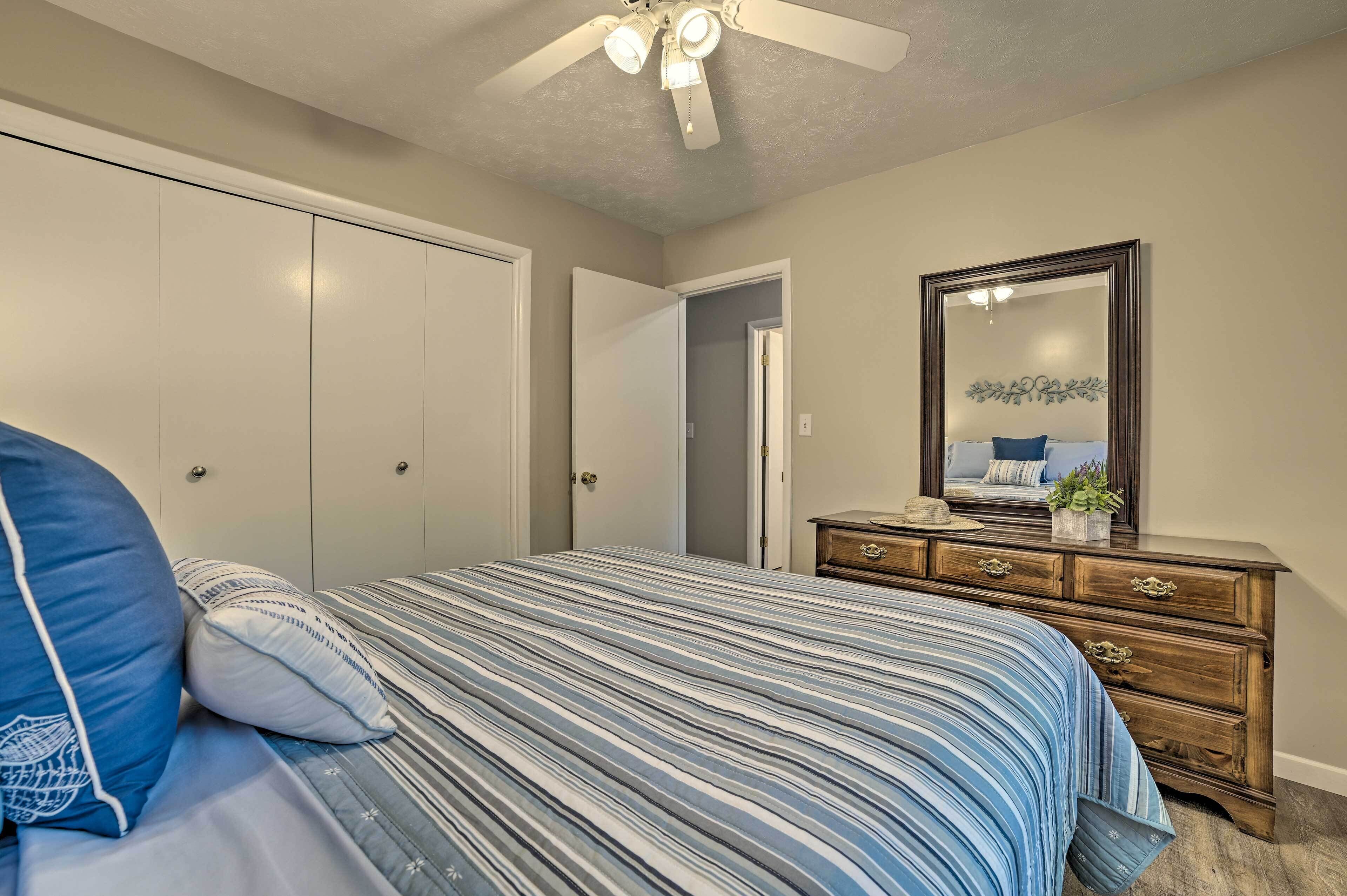 Un dormitorio con cama, cómoda, espejo y ventilador de techo.
