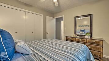 Un dormitorio con cama, cómoda, espejo y ventilador de techo.