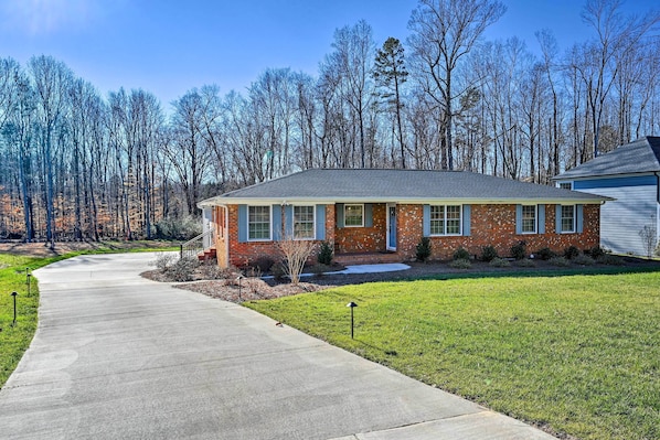 A single-story brick house with a front porch, a driveway, and a lawn. - Ranch-style Home 7 Mi to Downtown Greensboro! (Greensboro)