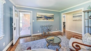 A living room with a glass coffee table, a patterned rug, a sofa, and a painting on the wall. - Ranch-style Home 7 Mi to Downtown Greensboro! (Greensboro)