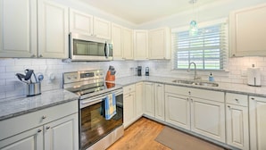 A kitchen with white cabinets, stainless steel appliances, a window with blinds, and a granite countertop. - Ranch-style Home 7 Mi to Downtown Greensboro! (Greensboro)