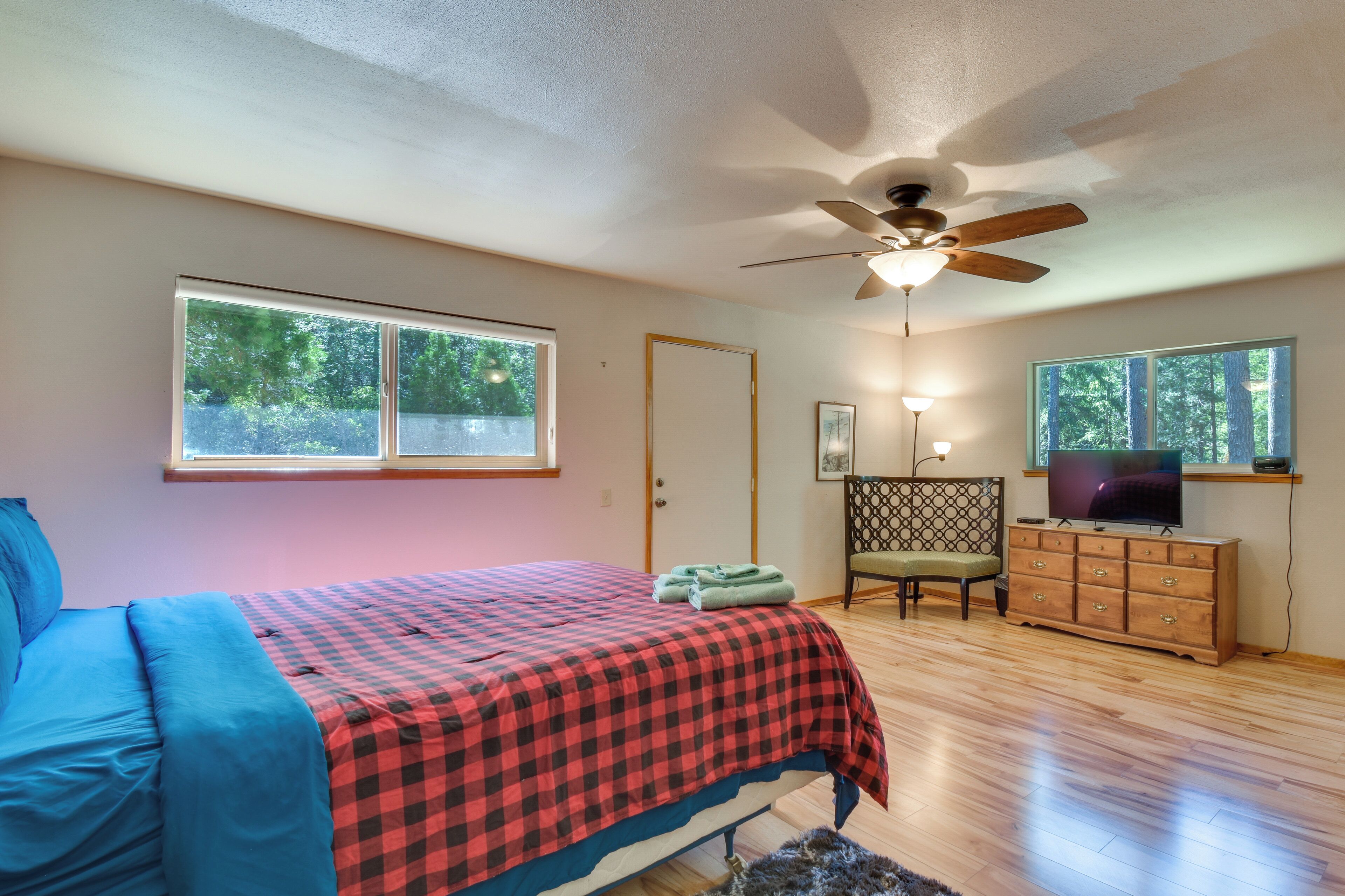 A bedroom with a bed, a ceiling fan, a dresser, a chair, and a TV.