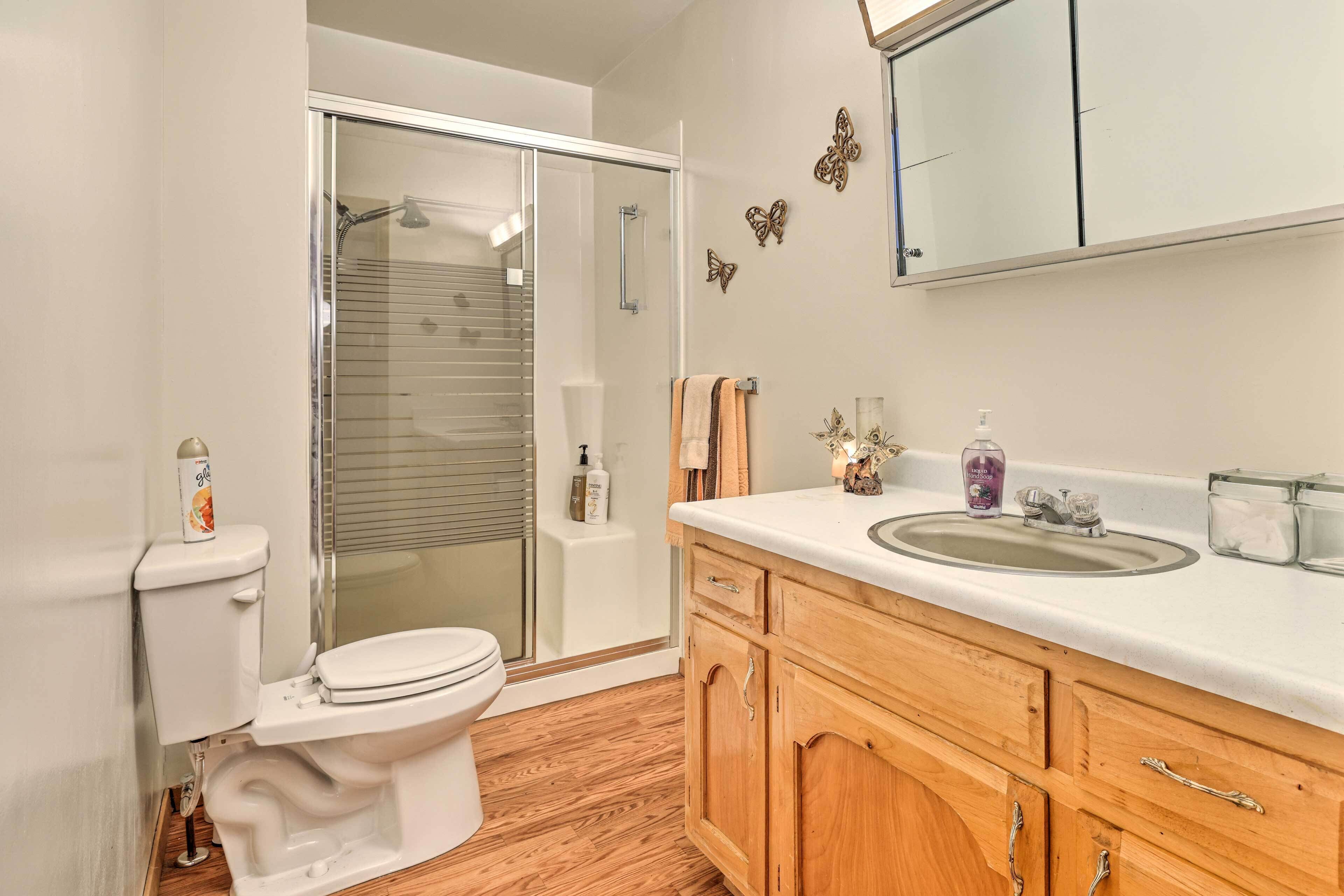 A bathroom with a toilet, shower, and sink.