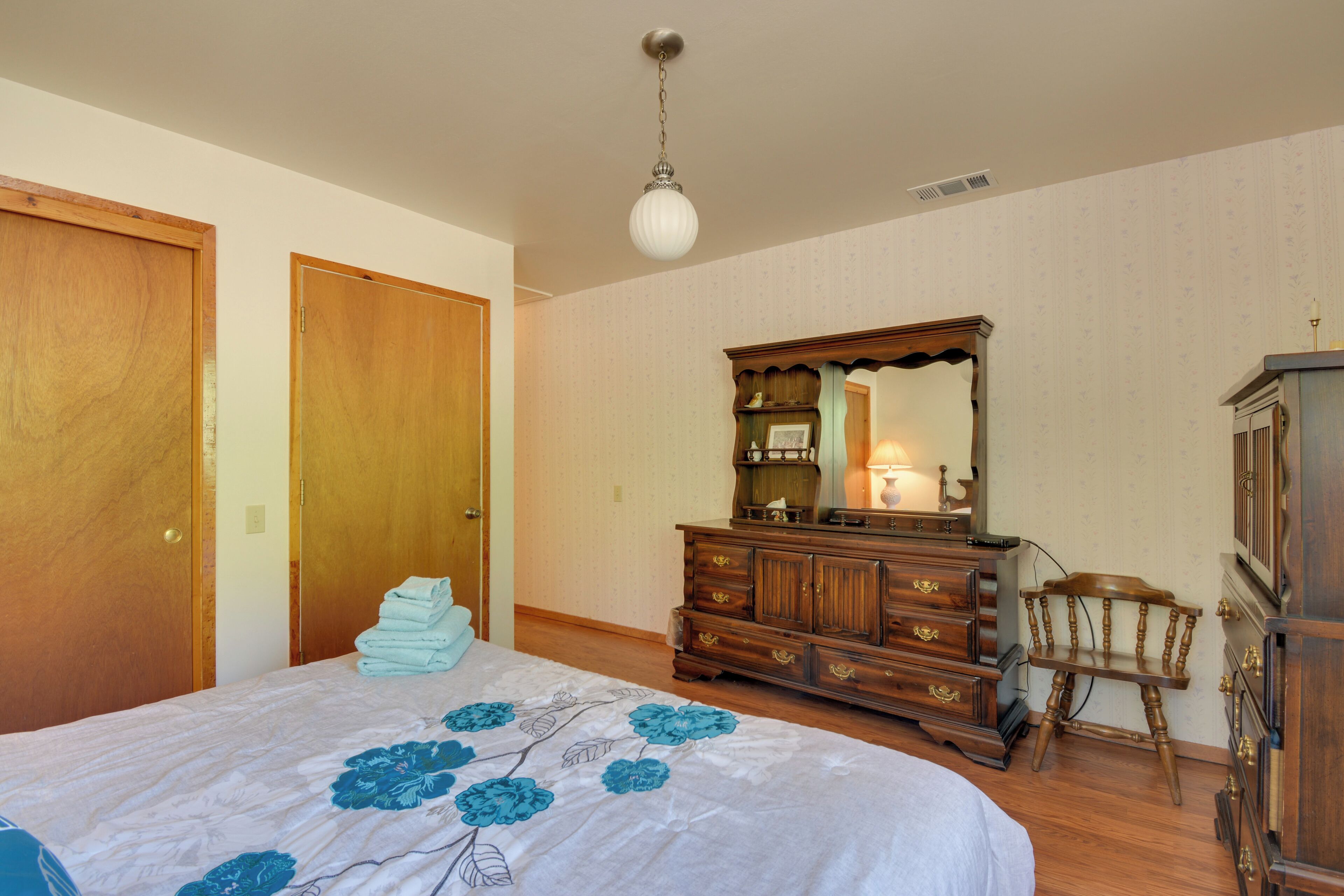 A bedroom with a bed, wooden dresser, and a chair.