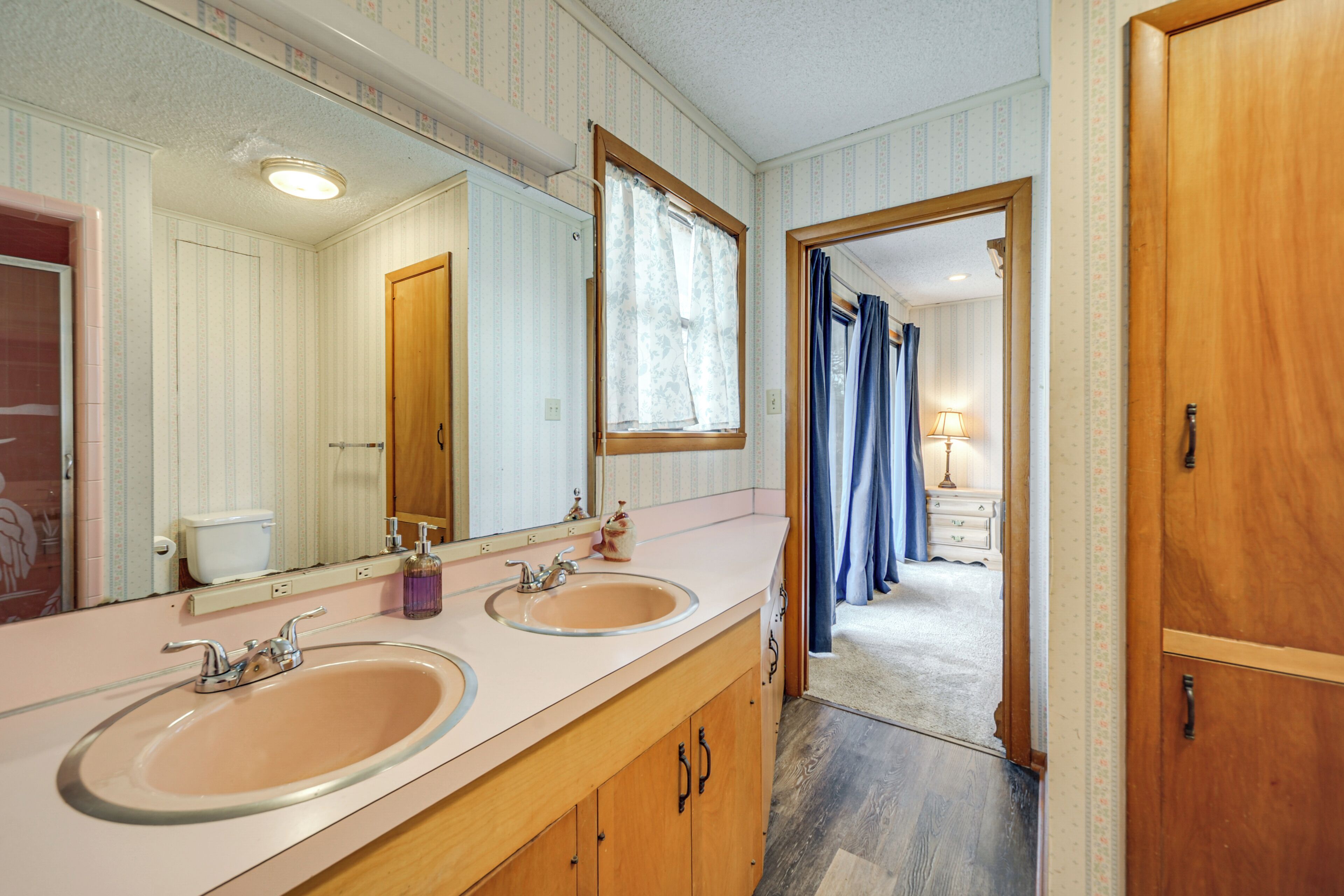 Een badkamer met twee wastafels, een grote spiegel en een houten deur.
