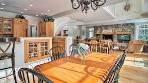 Une cuisine spacieuse avec des meubles en bois, un coin repas doté d’une grande table en bois et une cheminée en pierre.