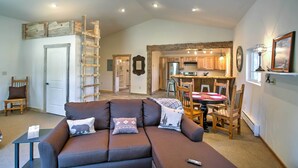 A spacious living area with a brown sofa, a dining table with chairs, a kitchen in the background, and a ceiling fan. - Mancos Cabin Rental on 80 Acres w/ Mountain View! (Mancos)