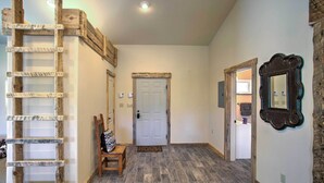 A hallway with a wooden ladder, a bench, a door, and a mirror on the wall. - Mancos Cabin Rental on 80 Acres w/ Mountain View! (Mancos)