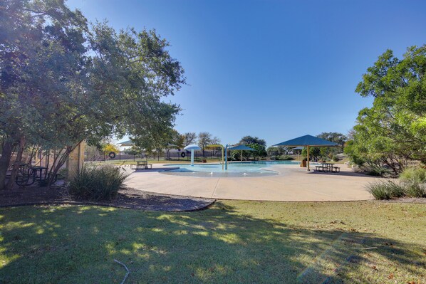 Un parque con piscina, mesas de picnic y zonas techadas.