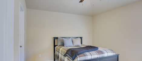 A bedroom with a bed, a ceiling fan, and wooden flooring.