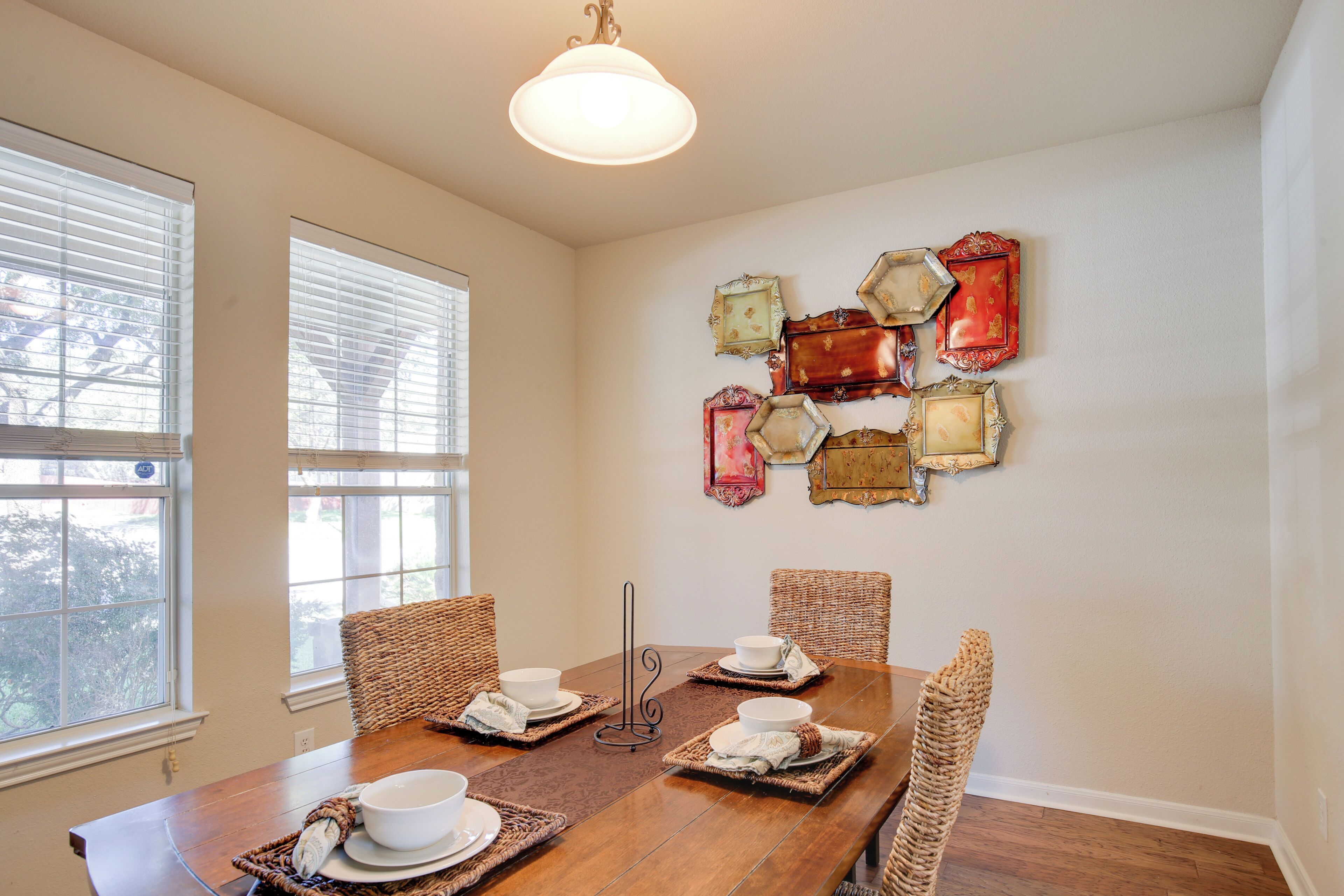 Comedor con una mesa de madera dispuesta para cuatro personas, rodeado de sillas de mimbre.